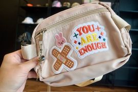 A tan bag decorated with playful custom patches.